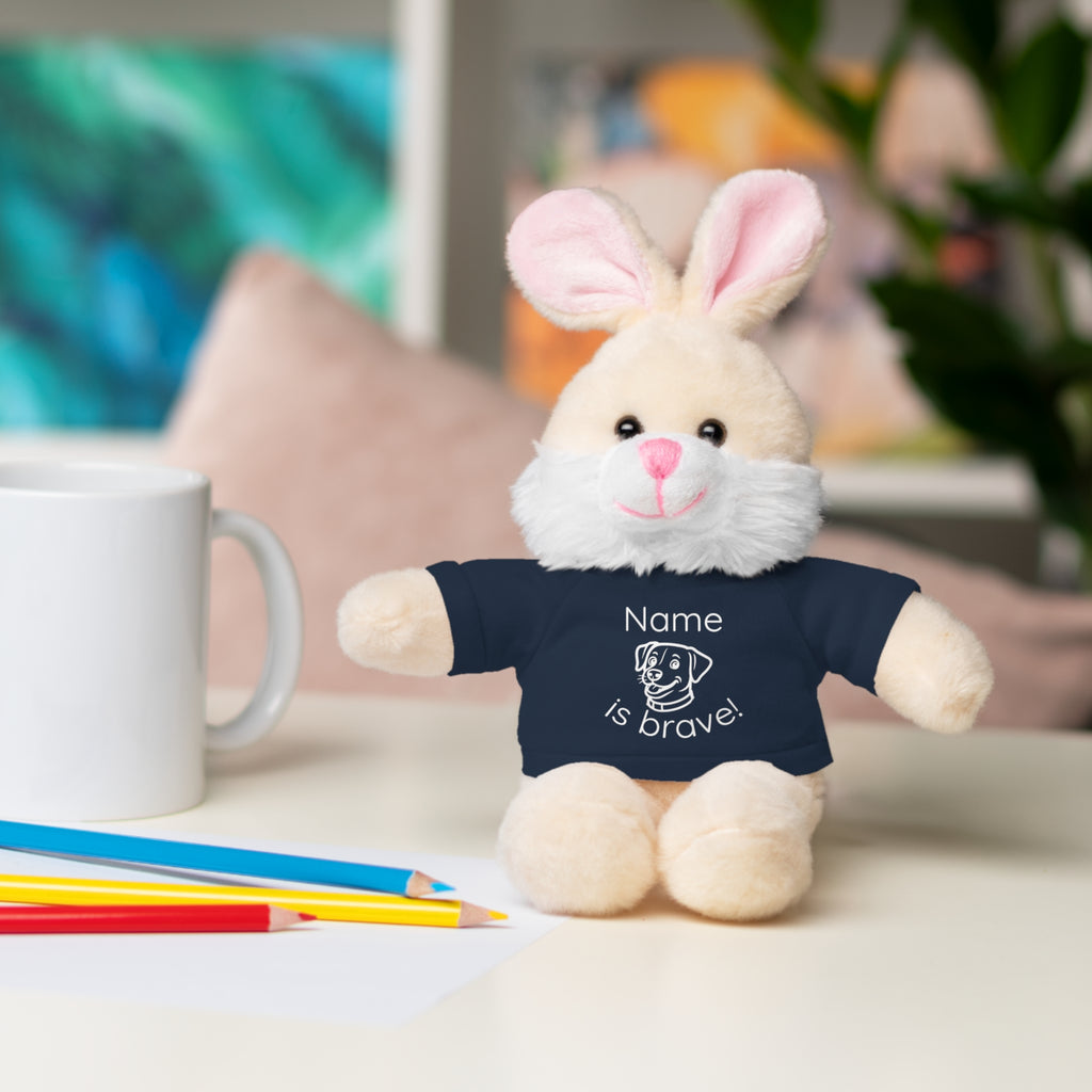 Soft off white plush bunny wearing a Name is Brave personalized navy  tee shirt - sitting on desk with colored pencils