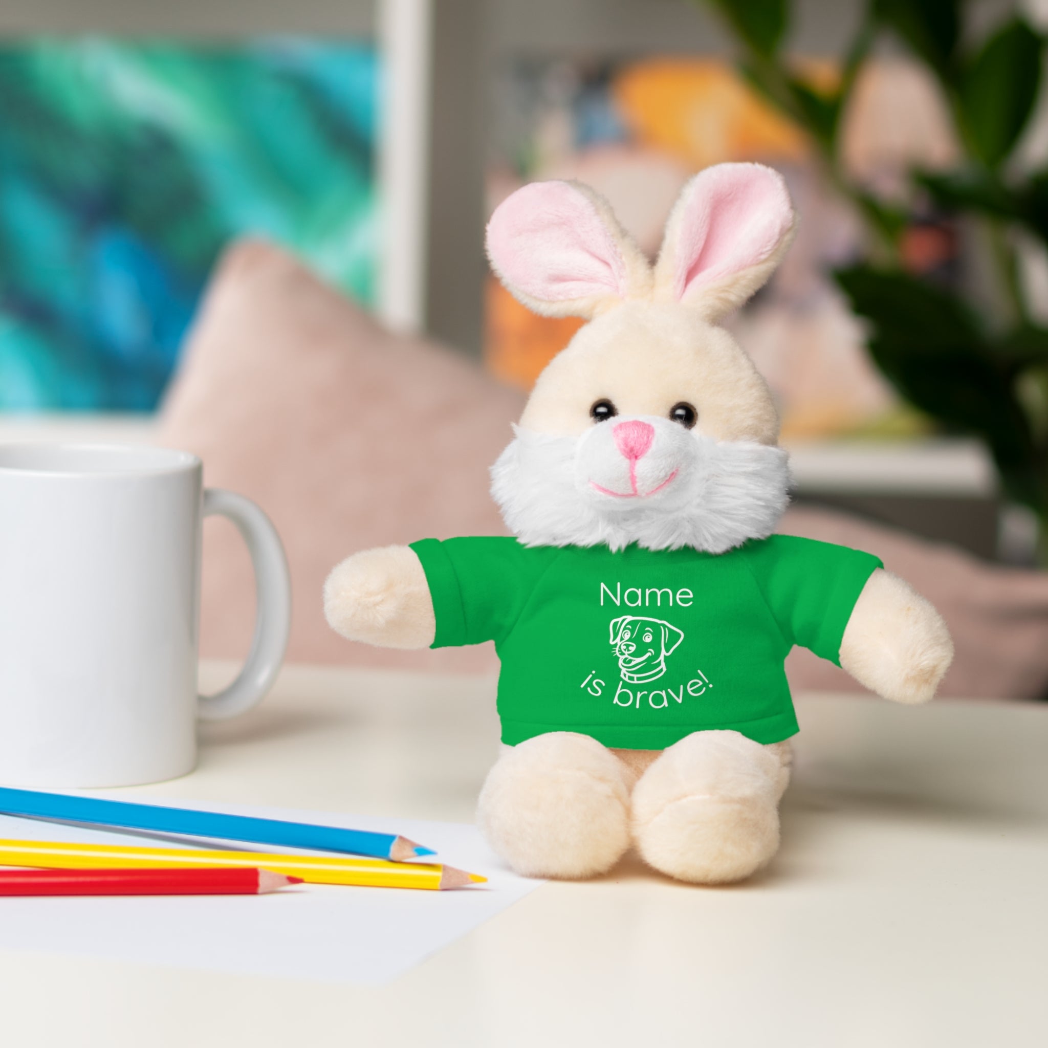 Soft off white plush bunny wearing a Name is Brave personalized irish green  tee shirt - sitting on desk with colored pencils