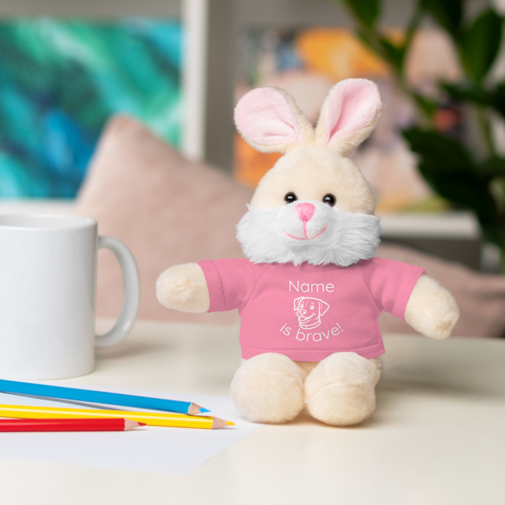 Soft off white plush bunny wearing a Name is Brave personalized pink  tee shirt - sitting on desk with colored pencils