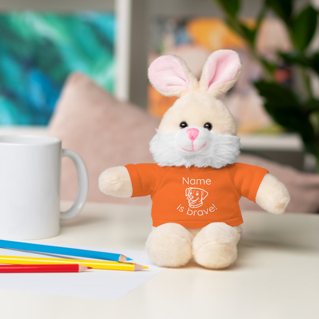 Soft off white plush bunny wearing a Name is Brave personalized orange  tee shirt - sitting on desk with colored pencils