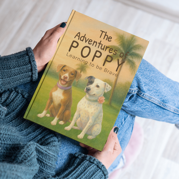 The Adventures of Poppy: Learning to be Brave hardcover book held by a person wearing blue jeans and a blue sweater