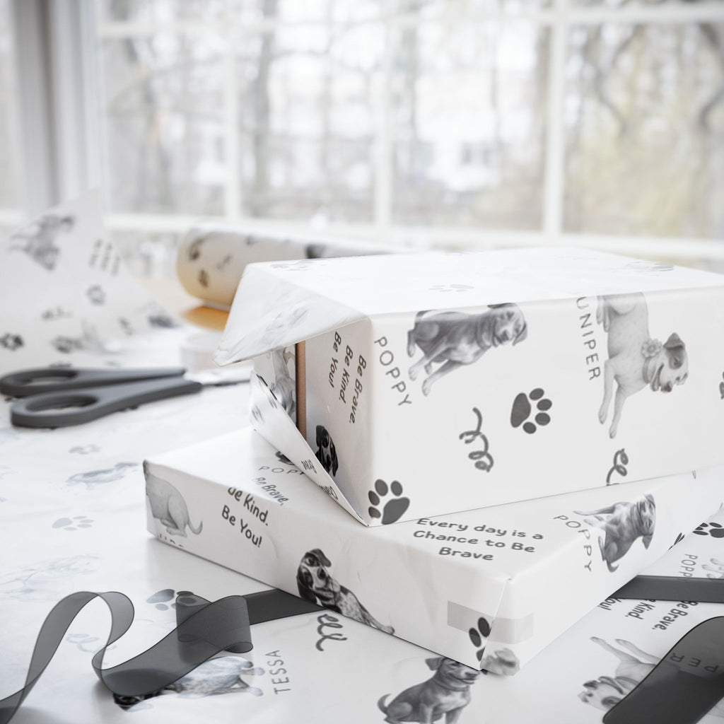 Boxes wrapped in The Adventures of Poppy neutral holiday wrapping paper in sitting in wrapping station with ribbon and sissors