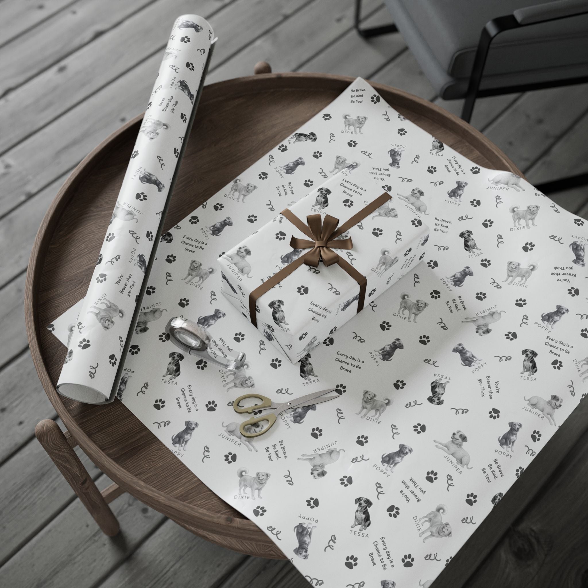 Box wrapped in The Adventures of Poppy neutral holiday wrapping paper in sitting beside roll and layed out on unrolled piece of wrapping paper